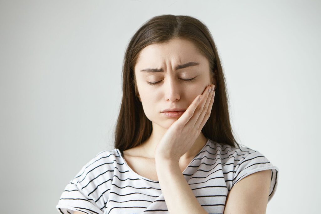 Clínica Dental Sorias - Blog - La posible relación entre el dolor de cabeza y el dolor de muelas - Mujer con dolor de muelas