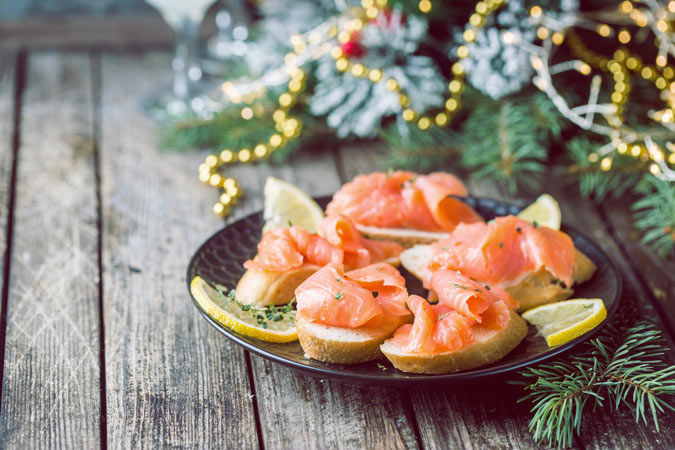 canapés de salmón en plato sobre mesa con decoración de Navidad